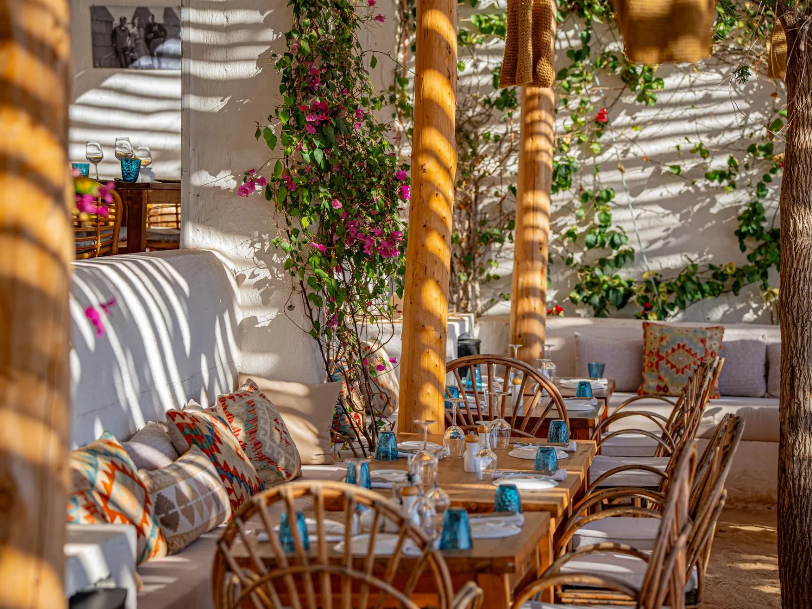 Charming outdoor Mediterranean-style restaurant with wooden furniture and vibrant flowers.